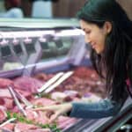 Woman pointing at meat in display at supermarket