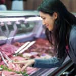 Woman pointing at meat in display at supermarket